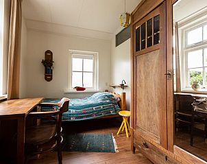 Kleine slaapkamer in Huisje in Tilligte, vakantieaccommodatie in Twente, Overijssel met houten meubels en kleurrijk dekbed.