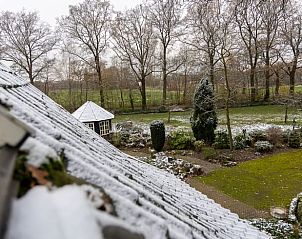 Besneeuwde tuin met vijver en prieel bij Huisje in Oldenzaal vakantiehuis in Twente, Overijssel.