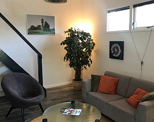 Comfortabele zithoek in vakantiehuis in Vroomshoop, Twente, met kunst aan de muur.