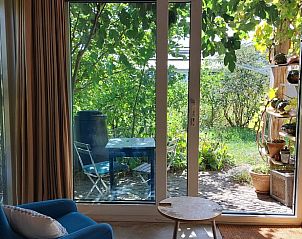 Zonnig uitzicht vanuit de woonkamer van Vakantiehuis in Olst, Salland met groene tuin.