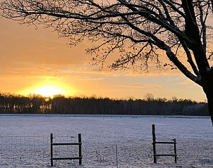 Adembenemende zonsondergang bij Huisje in Bruchterveld, omringd door natuur.