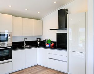 Strakke keukeninrichting in Vakantiehuis CamperSand, Kampen, Overijssel, voorzien van moderne apparatuur en een minimalistisch design.