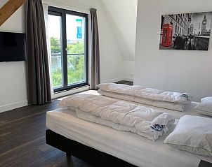 Slaapkamer in Familievilla 12, een vakantiehuis in Ossenzijl, Overijssel, met uitzicht op de natuur door grote ramen.