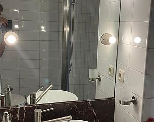 Badkamer met spiegel en wastafel in Vakantiehuisje in Tuk, biedt comfort in Noordwest Overijssel.