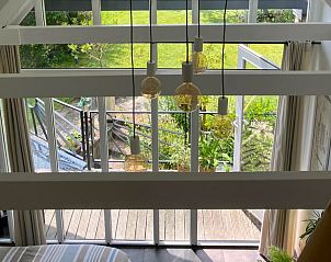 Light-filled interior of vacation home OV735 in Tuk, Overijssel, overlooking green garden and modern pendant lights.