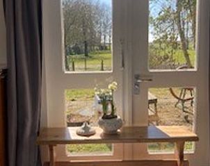 Zonnige zithoek in Vakantiehuisje in Basse, Overijssel, met uitzicht op de groene omgeving.