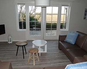 Gezellige woonkamer in strandhuis De Bakkeete, Kamperland, met uitzicht op de landelijke omgeving van Noord-Beveland, Zeeland.