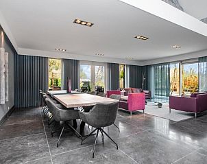 Gezellige eetkamer in Het Vinkenest bungalow, Oud-Alblas, met uitzicht op de tuin, perfect voor familiebijeenkomsten in Zuid-Holland.