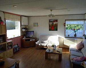 Zonnige woonkamer in Het Zomernest, Ouddorp, met grote ramen en comfortabele banken.