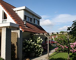 Zijaanzicht van Vakantiebungalow Herkingen, met kleurrijke bloemen in Herkingen, Goeree-Overflakkee. Perfect voor natuurliefhebbers.