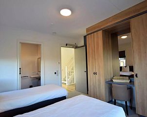 Slaapkamer met tweepersoonsbed en eigen badkamer in Villa Kaagervaaring, vakantiehuis in Kaag, Zuid-Holland.