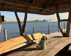 Houten tafel onder rieten dak met uitzicht op de rivier bij Vakantiehuis in Ammerstol.