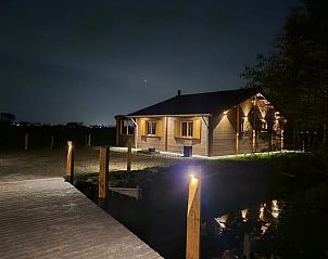 Vakantiehuisje in Ameide verlicht in de nacht, biedt een warme en uitnodigende sfeer.