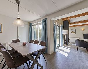 Eethoek in K7A bungalow, Kijkduin, met uitzicht op de tuin en veel natuurlijk licht.