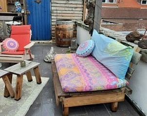 Gezellige zithoek op het terras van Vakantiehuis aan zee, Katwijk aan Zee, Noordzeekust, Zuid-Holland, met kleurrijke kussens en decoratie.