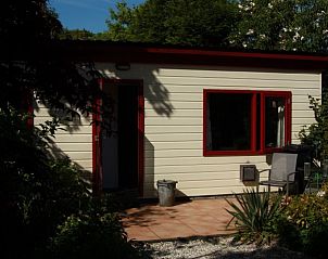 Zonnig terras bij Om de Loop vakantiehuis in Rockanje, Zuid-Holland, omgeven door groen.