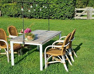 Buitenterras met tuinmeubilair bij DE DIJK bed and breakfast, omgeven door groene natuur.