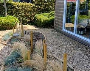 Landschappelijk aangelegde tuin bij Pinquin 31 vakantiehuis in Rockanje, met siergrassen en privacy in Voorne Putten, Zuid-Holland.