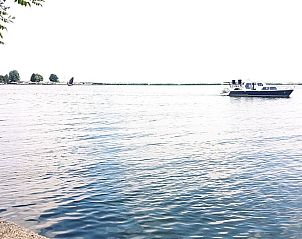 Een boot vaart langs het Vakantiehuisje in Bleiswijk, een perfecte plek voor watersport in Rotterdam eo, Zuid-Holland.